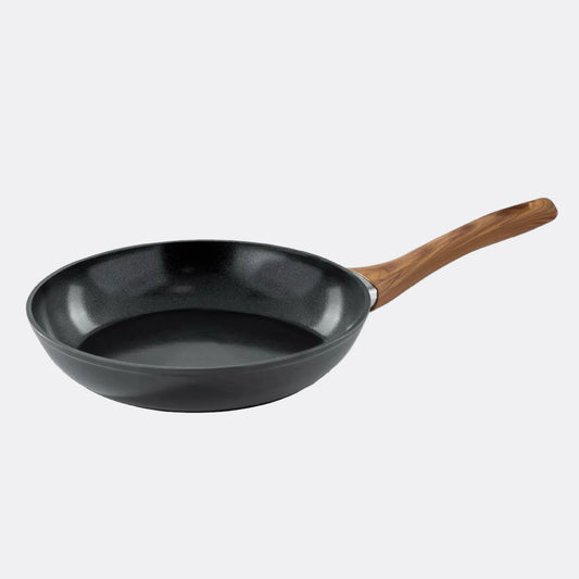 Black frying pan with a wooden handle on a light grey background